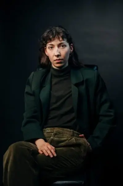 A female cast member sat looking at the viewer